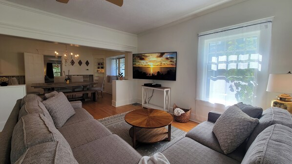 A spacious living room with a large sofa, a coffee table, and a flat-screen TV mounted on the wall. - Rosewood Collective- House & Studio (Medford)
