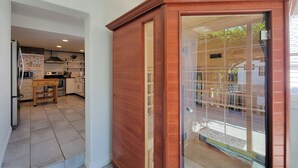Eine moderne Küche mit weißen Schränken, einem Holztisch und einer Schiebeglastür, die auf einen Balkon führt.