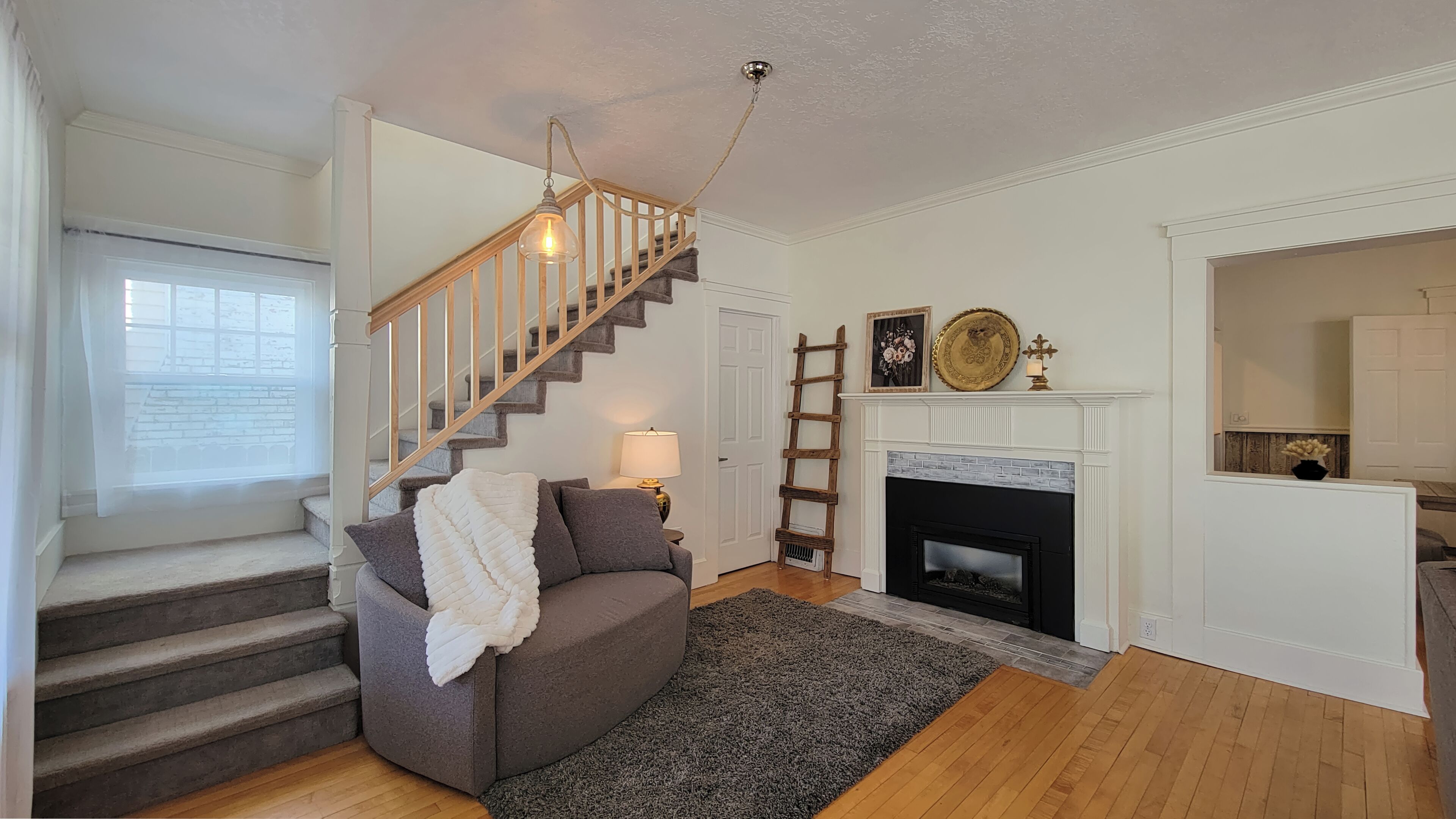 A living room with a staircase, a fireplace, and a couch.