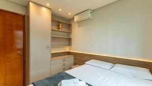 Une chambre d’hôtel équipée d’un lit, d’une armoire, d’une étagère et d’un appareil de climatisation.