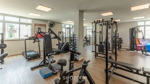 Une salle de sport équipée de divers appareils d’exercice, dotée de grandes fenêtres et d’un plancher en bois.