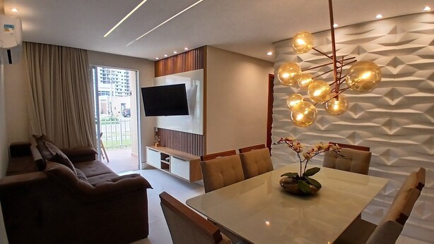 Un salon moderne doté d’un téléviseur à écran plat, d’une table à manger avec des chaises, d’un canapé et d’un luminaire décoratif.