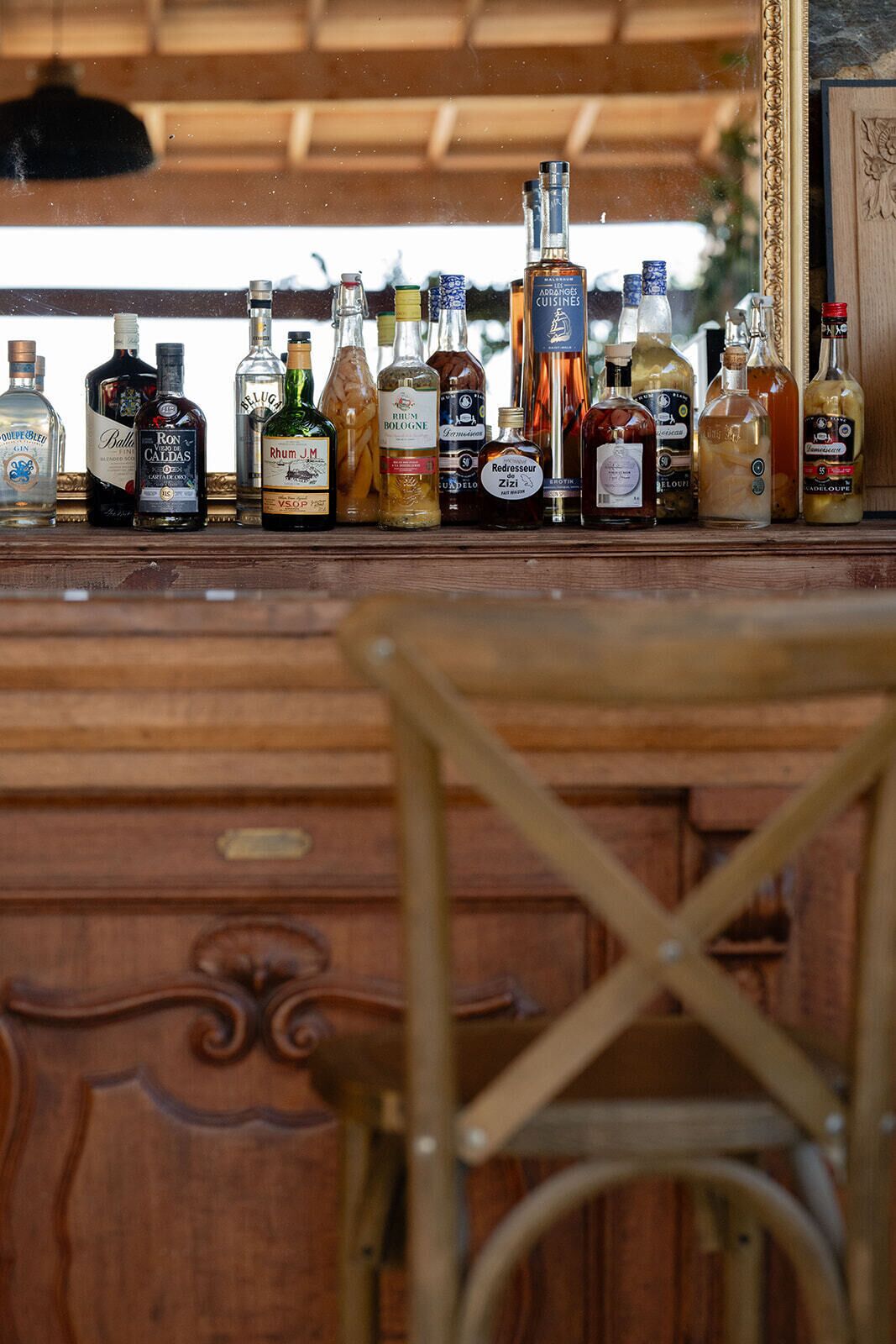 A bar area with a variety of liquor bottles and a wooden chair in the foreground.