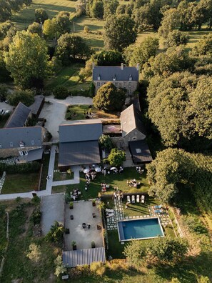 Vista aérea de uma propriedade com um edifício grande, piscina e vegetação ao redor.