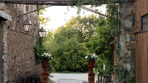 A stone building with a wooden archway leading to a paved path. - Domaine du Tertre ychot (Dol-de-Bretagne)