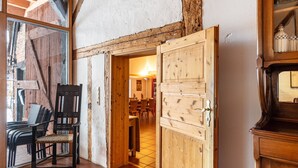 Un intérieur rustique avec une porte en bois donnant sur un coin repas, une chaise et un buffet.