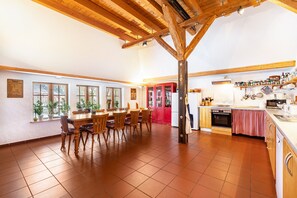 A spacious kitchen with wooden beams, a dining area with chairs, and a red door. - Holiday Home 'Ole Schün Dannau' with Private Terrace, Private Garden and Wi-Fi (Oldenburg in Holstein)