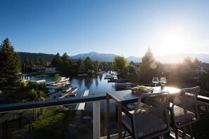 A terrace with a view of a lake, boats, and mountains.