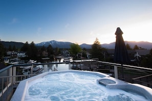 A hot tub with a view of mountains and a lake.