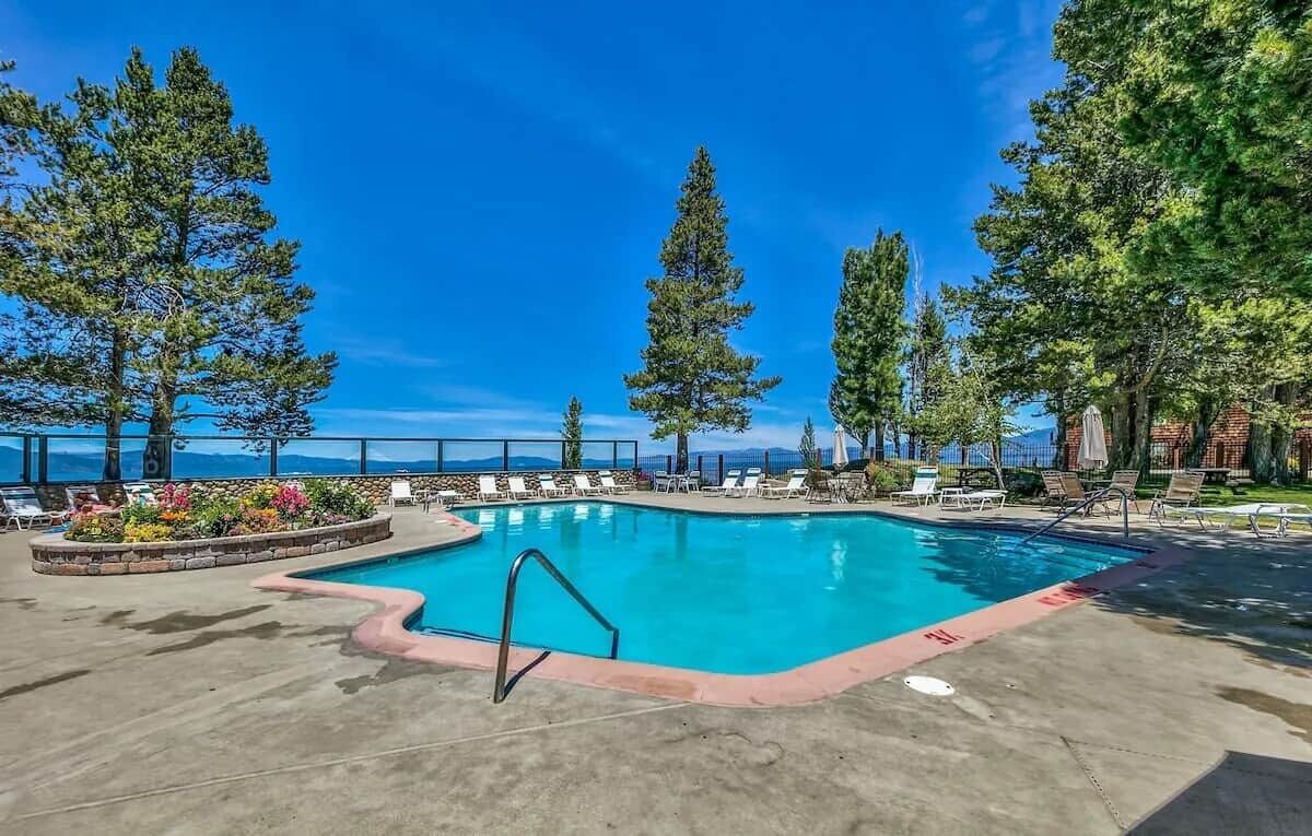 A swimming pool with lounge chairs and a view of the ocean.