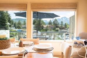 A dining area with a table set for two, overlooking a lake with mountains in the background.