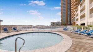 Un espace piscine avec des chaises longues et, en arrière-plan, un grand immeuble.