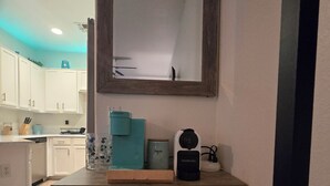 Een keuken met witte kastjes, een koffieapparaat en een waterdispenser in turquoise.