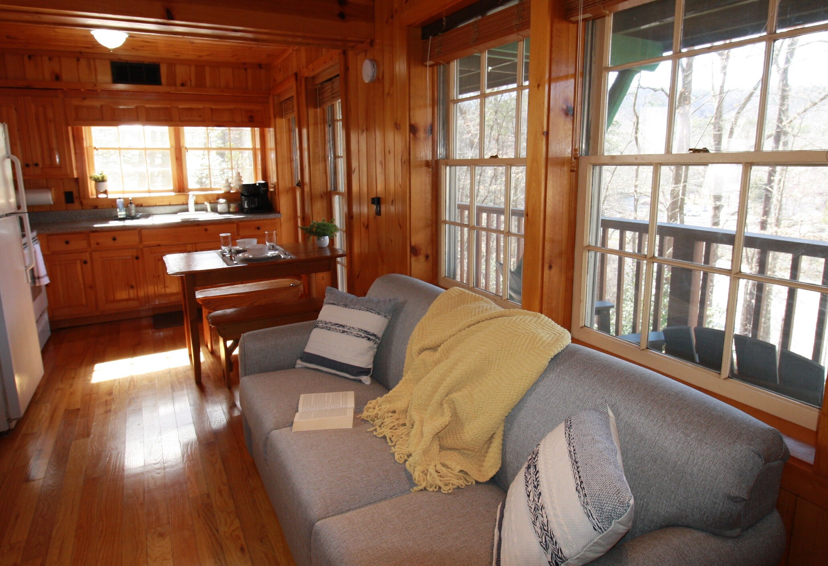 A wooden cabin interior with a sofa, dining table, and kitchen area.