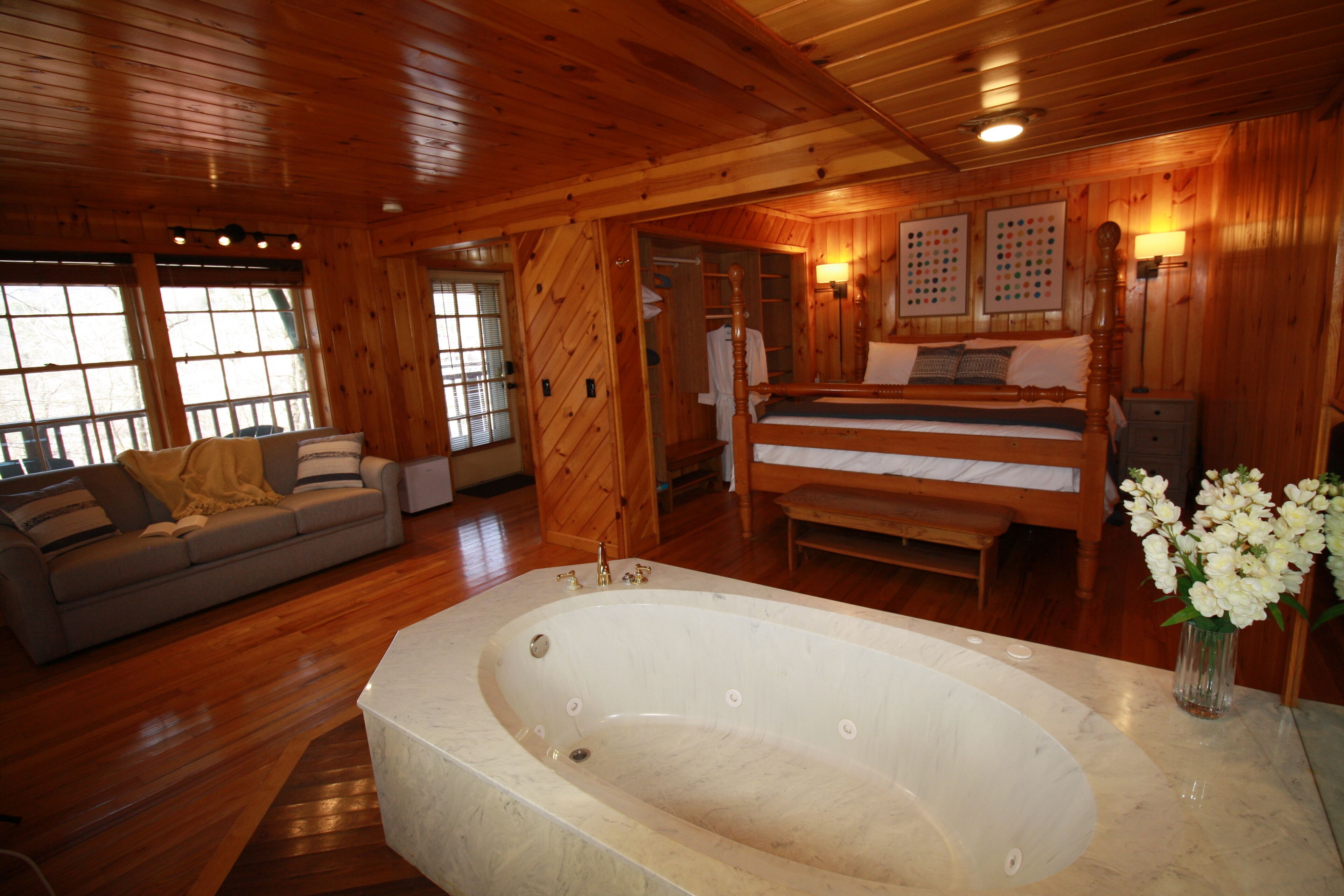 Een ruime kamer met een groot bad, houten wanden, een bank en een bed.