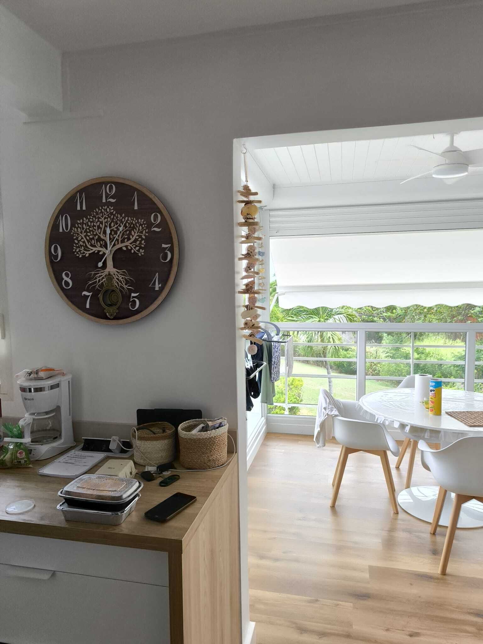 Eine moderne Küche mit Holztischplatte, einer Kaffeemaschine und einer Wanduhr mit Baummotiv.