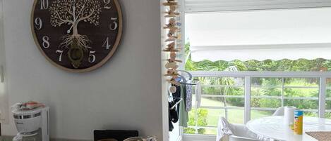 A modern kitchen with a wooden counter, a coffee machine, and a wall clock with a tree design.