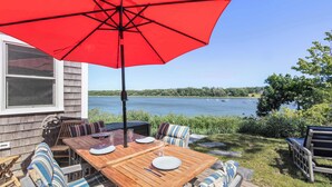 Une terrasse extérieure avec une table en bois, des chaises et un parasol rouge.