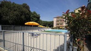 A pool area with yellow umbrellas, lounge chairs, and a fenced pool. - Bright Flat in Rosolina With Shared Pool (Rosolina)