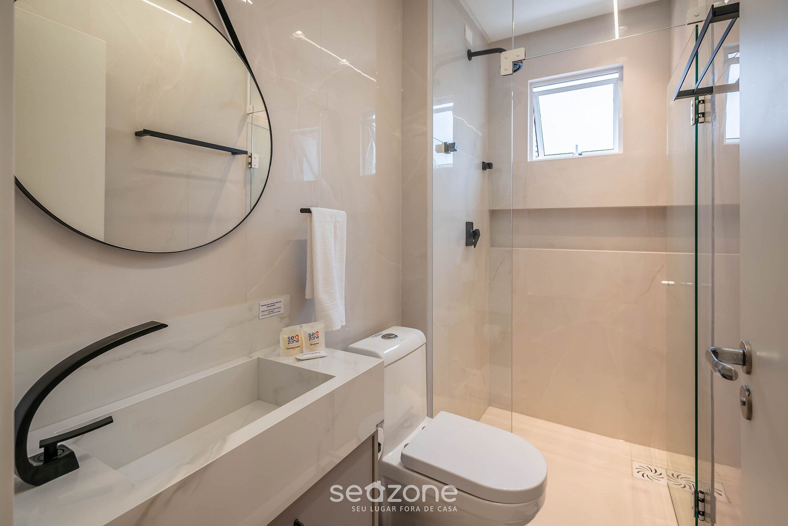 A modern bathroom with a glass shower enclosure, a white toilet, and a large mirror.