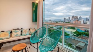 Un balcone con vista sulla città, un divano con cuscini e due poltrone.