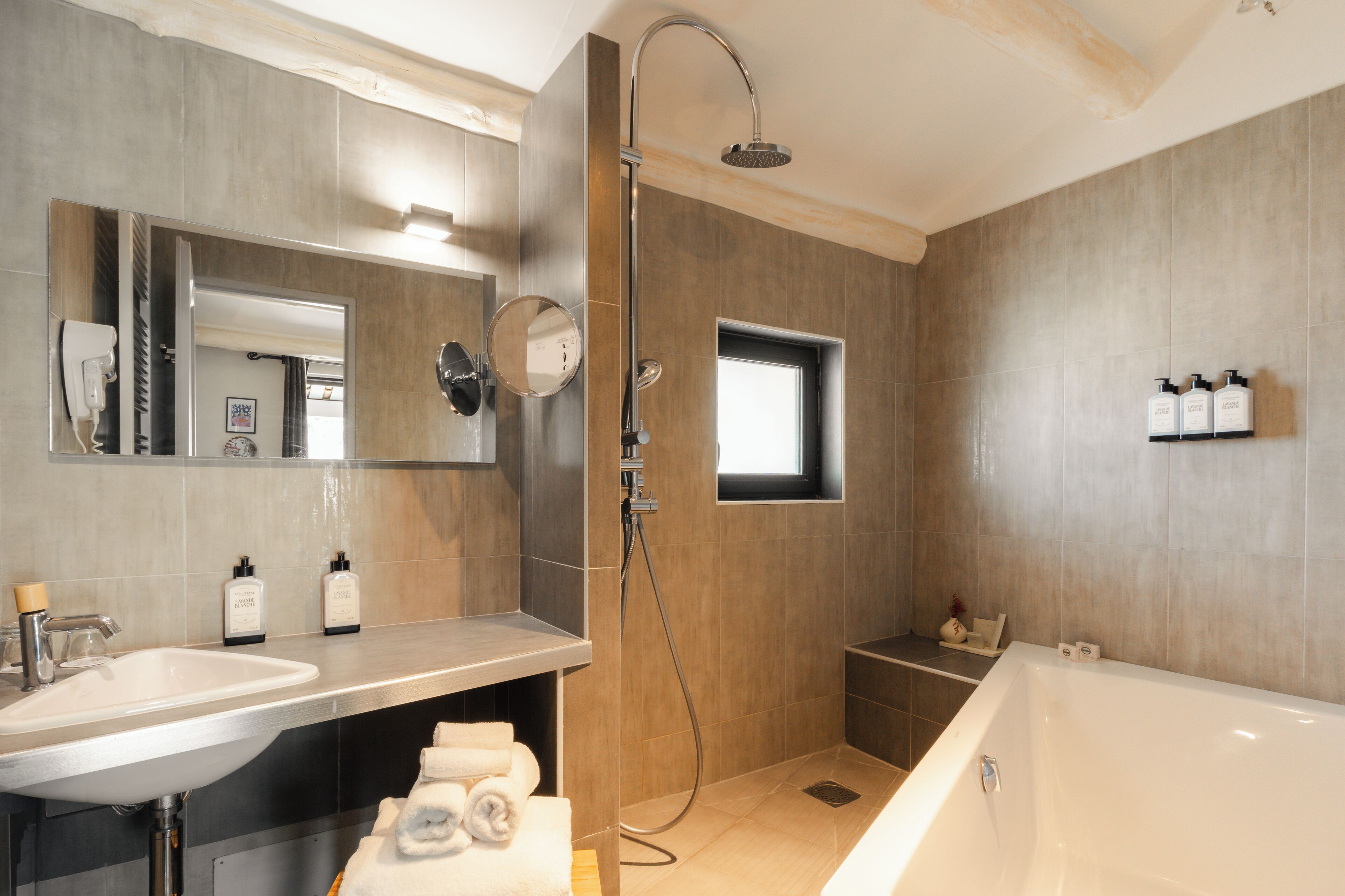 A modern bathroom with a bathtub, a shower, a sink, and a mirror.