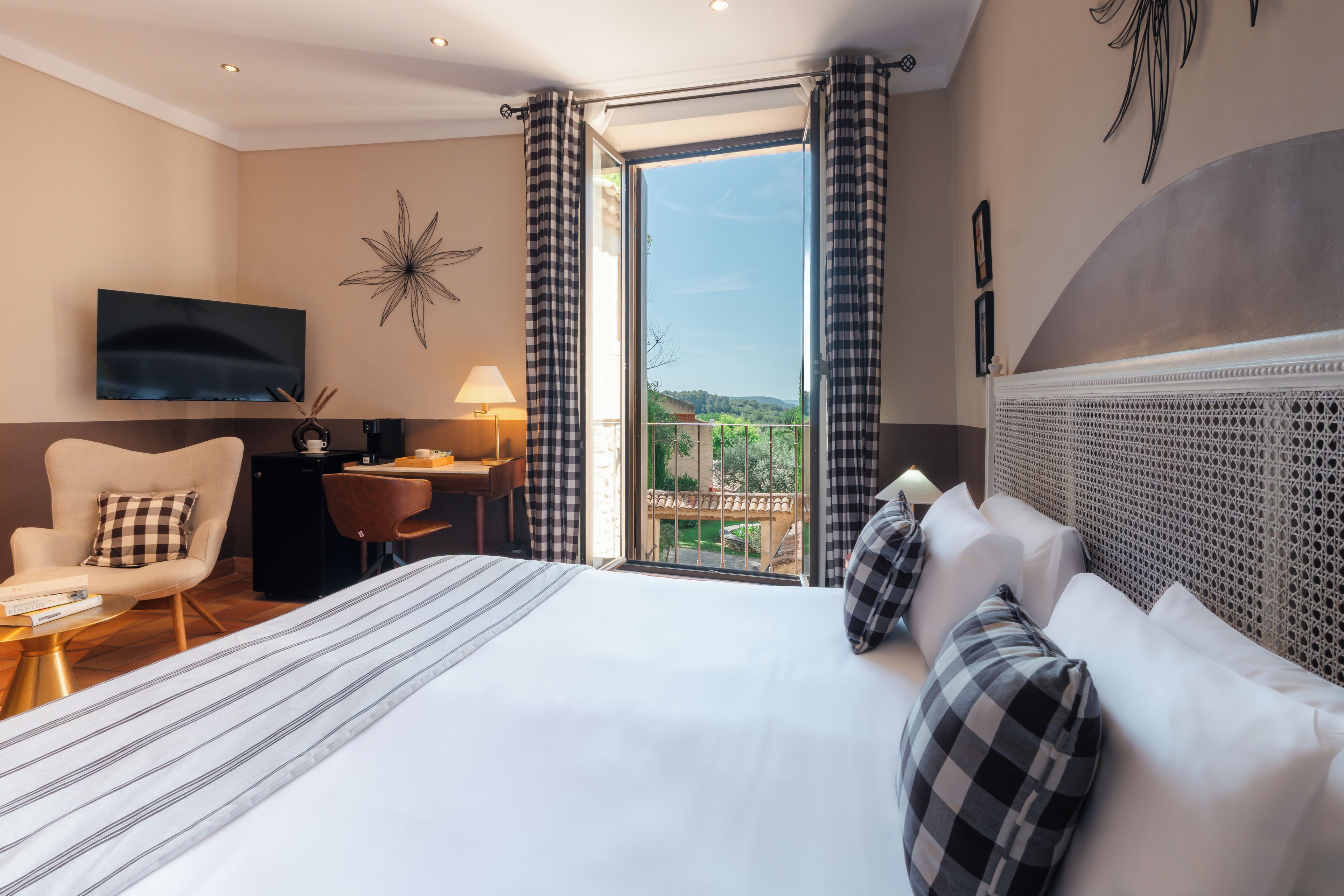 A hotel room with a large bed, a desk, a chair, a television, and a view of the outdoors.
