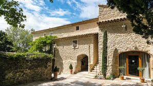A stone building with a reception area, a staircase, and potted plants. - Le Mas de Guilles (Lourmarin)
