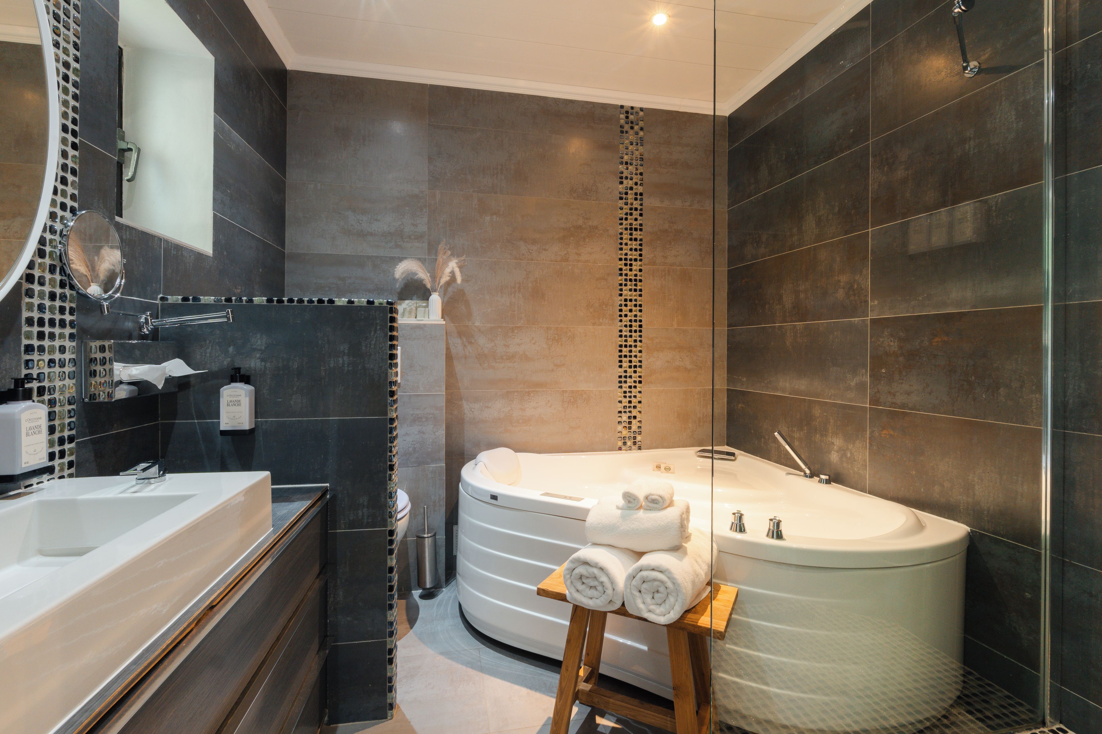 A modern bathroom with a large bathtub, a separate shower area, and a vanity with a mirror and sink.