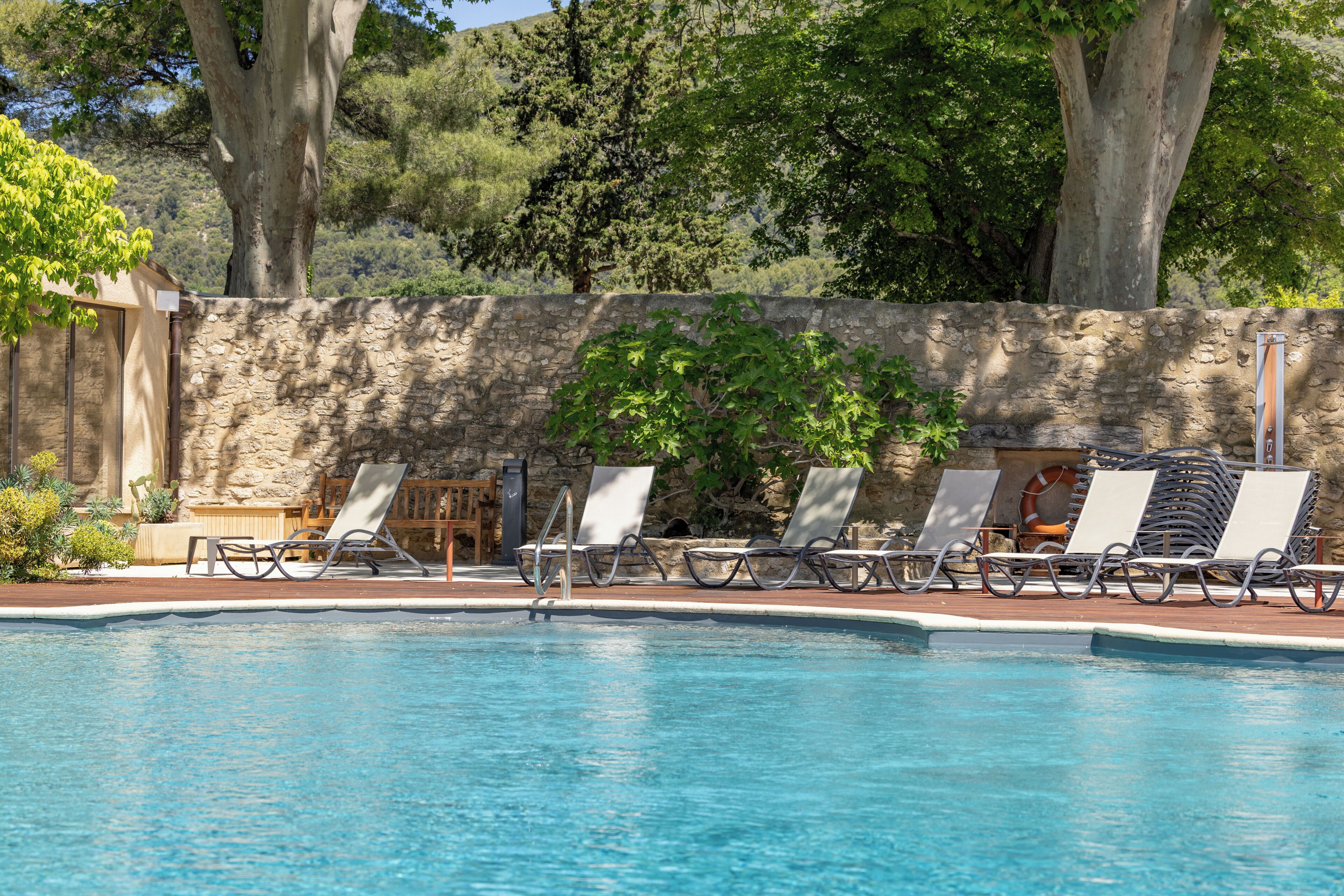 Ein Pool mit Liegestühlen und einer Steinmauer.