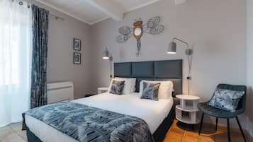Una habitación de hotel moderna con una cama grande, dos mesitas de noche, una silla, un adorno en la pared y una ventana con cortinas.