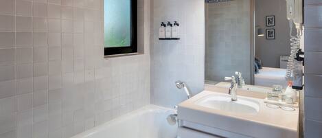 A modern bathroom with a bathtub, a sink, and a window.