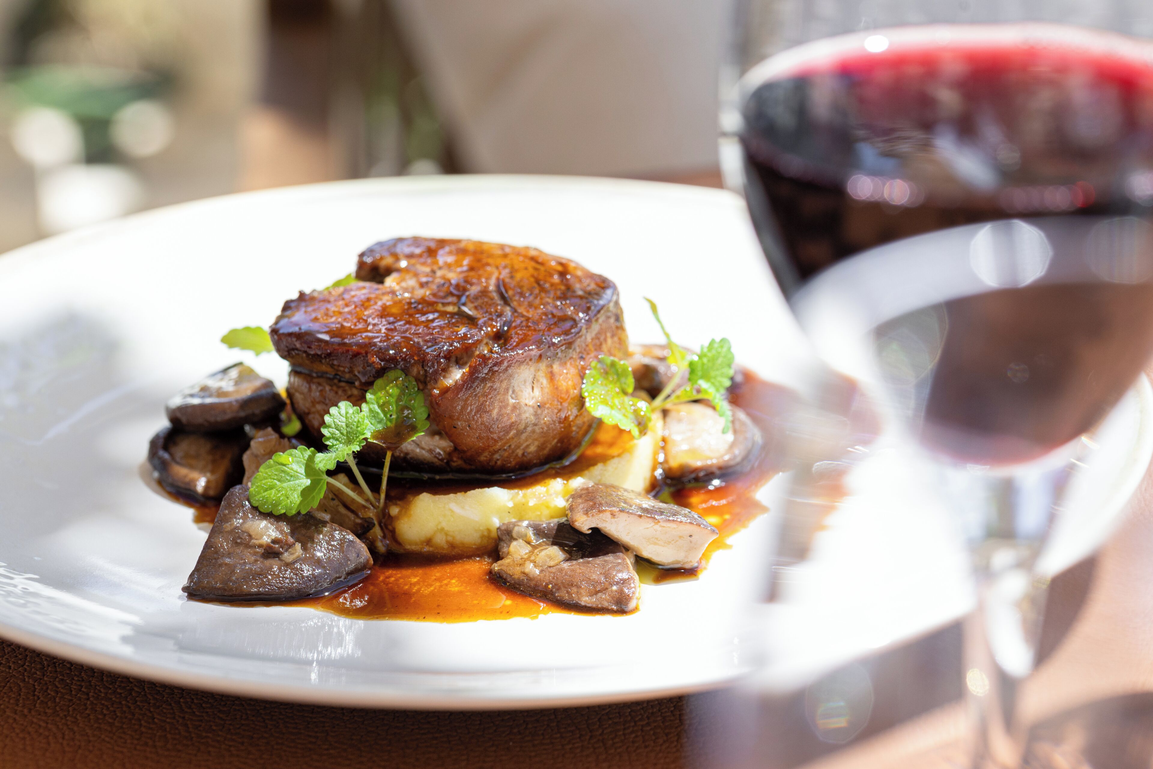 A plate of food with mushrooms and a glass of red wine.