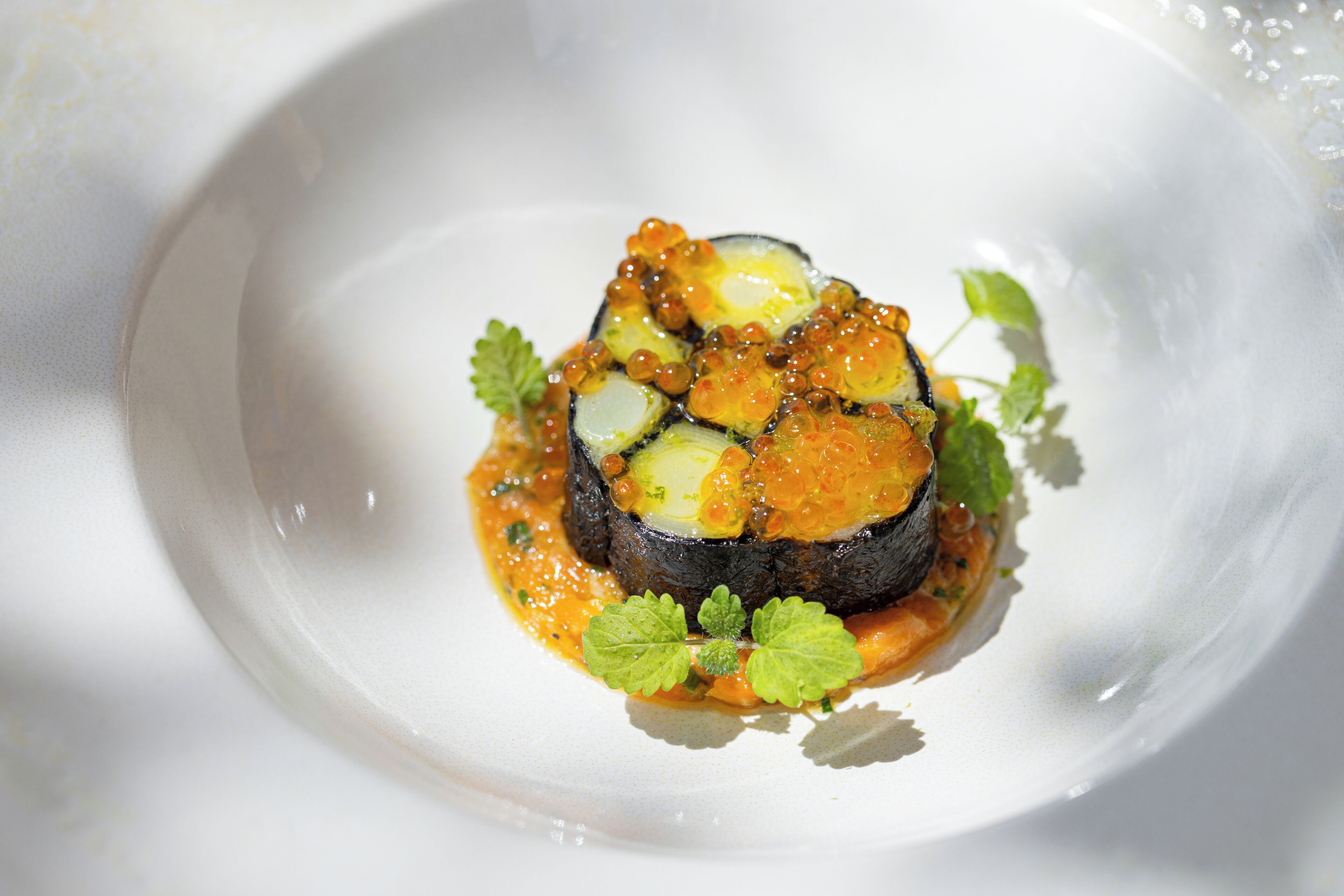 A white plate with a dish of food, garnished with green leaves.