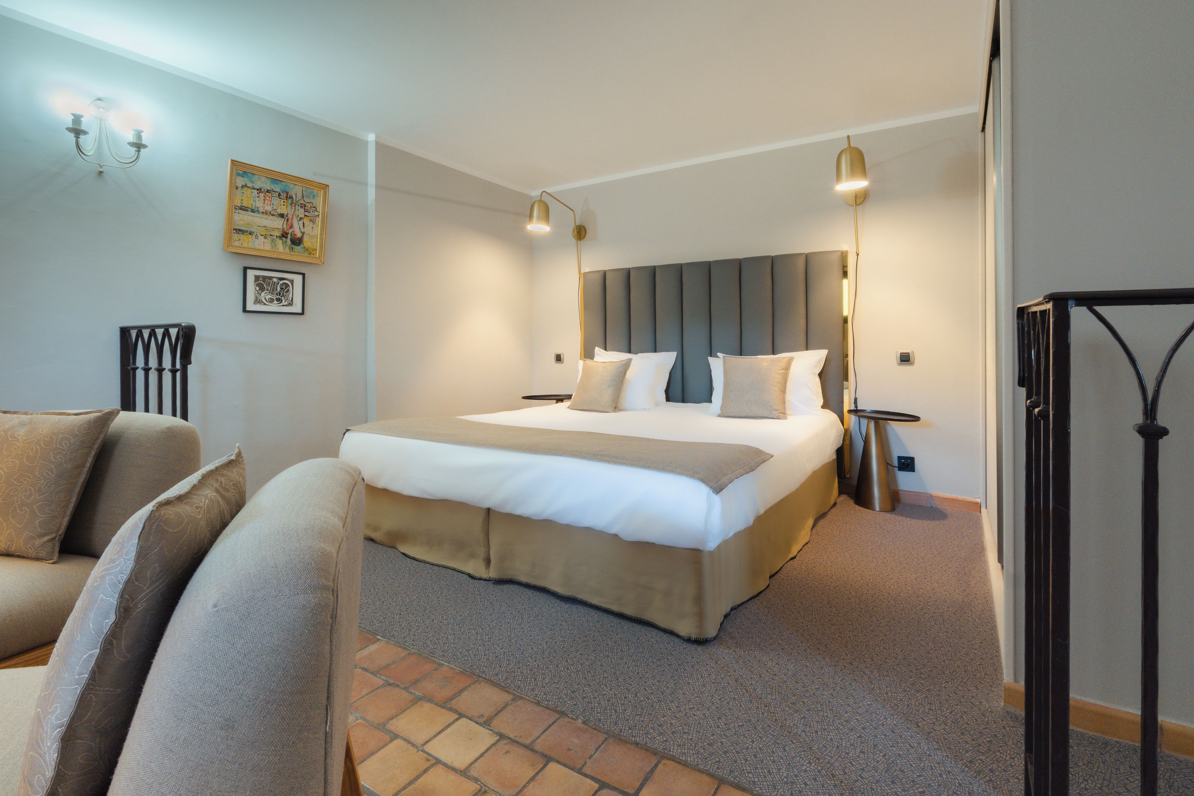 A hotel room with a large bed, a bedside table, a chair, and a floor lamp.