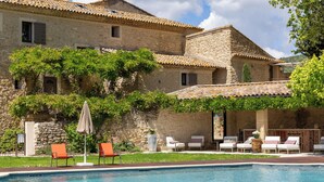 A stone building with a swimming pool, outdoor seating, and greenery. - Le Mas de Guilles (Lourmarin)