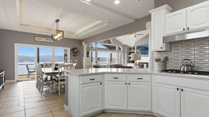Una cucina moderna con mobili bianchi, un'isola grande e vista sull'esterno.