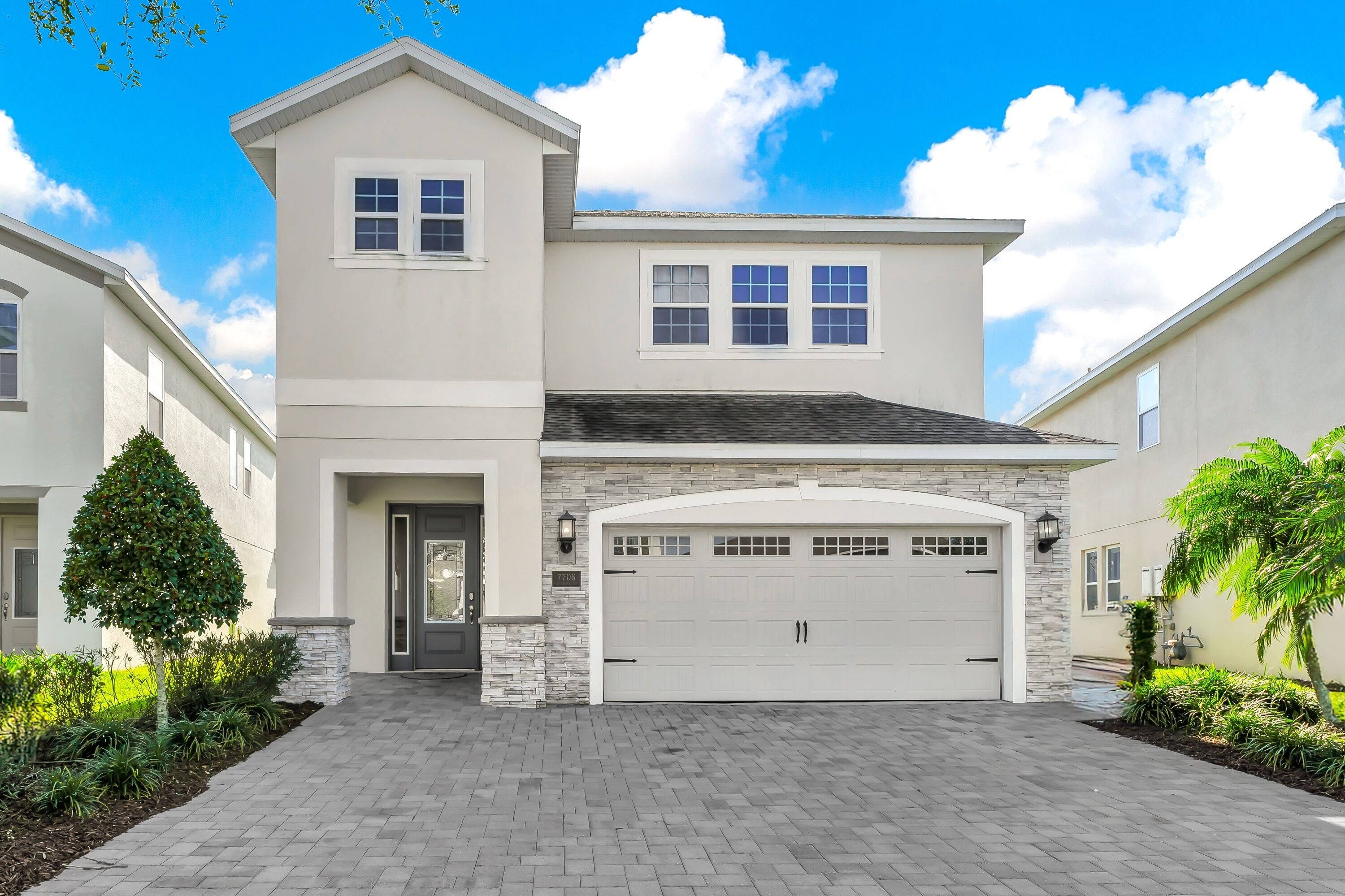 A modern two-story house with a garage, stone accents, and a well-maintained driveway.