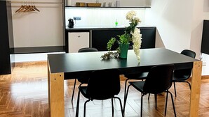 A modern dining area with a black table and chairs, a potted plant, and a kitchen in the background. - The Apartment Agrigento (Agrigento)