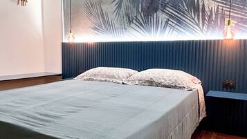 A bedroom with a bed, a wall-mounted light fixture, and a large wall art piece.