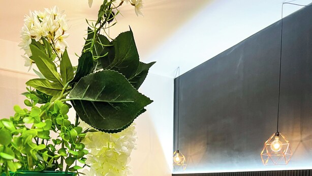 A modern hotel room with a bed, bedside table, and a green vase with white flowers. - The Apartment Agrigento (Agrigento)