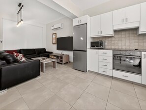 Eine moderne Küche mit weißen Schränken, einem Edelstahlkühlschrank, einer Mikrowelle und einem Backofen.