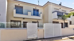 Ein zweistöckiges Gebäude mit weißer Fassade, einem verschlossenen Eingang und einem kleinen Balkon im oberen Stockwerk.