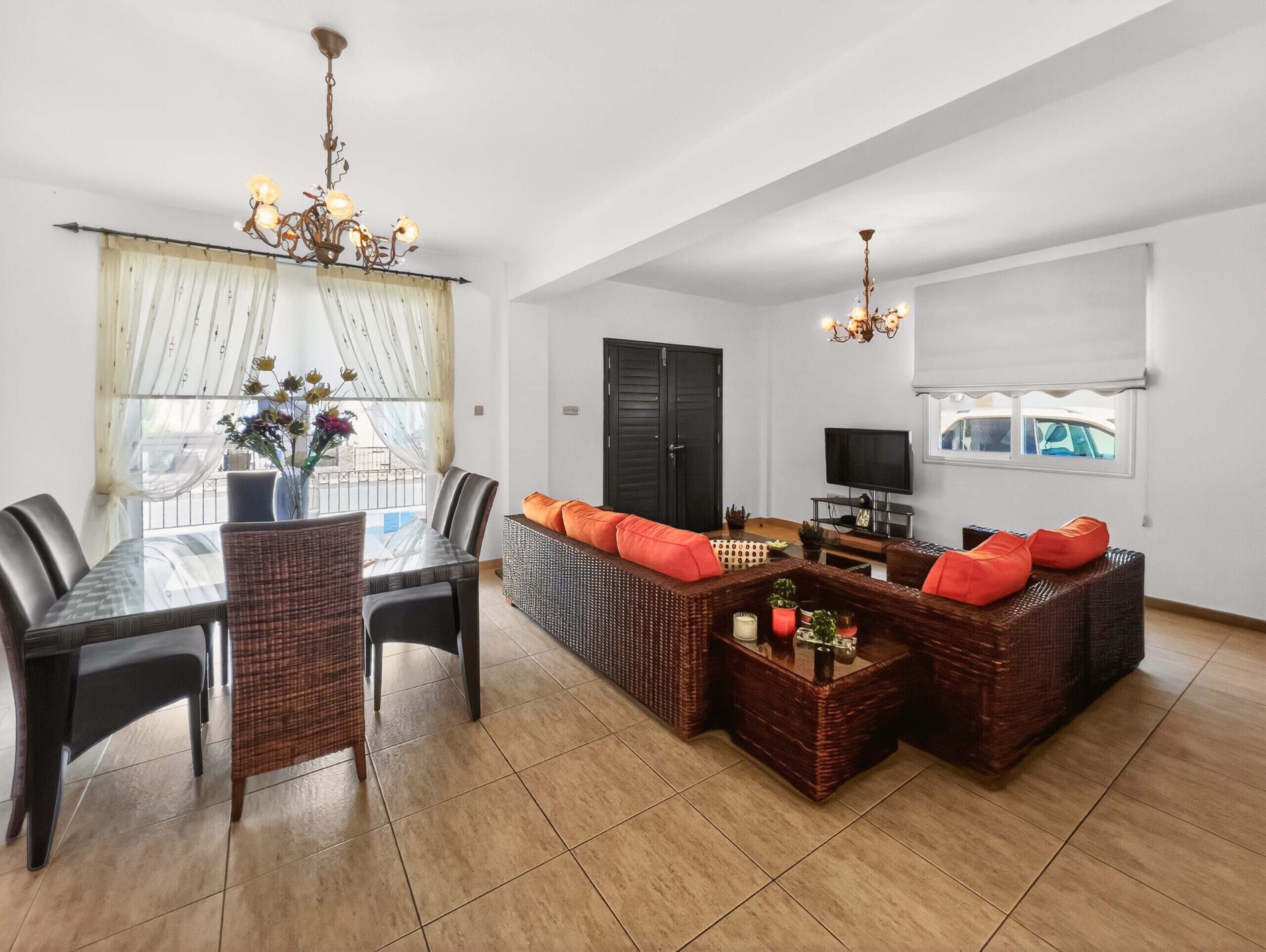 A spacious living area with a dining table, sofas, and a TV.