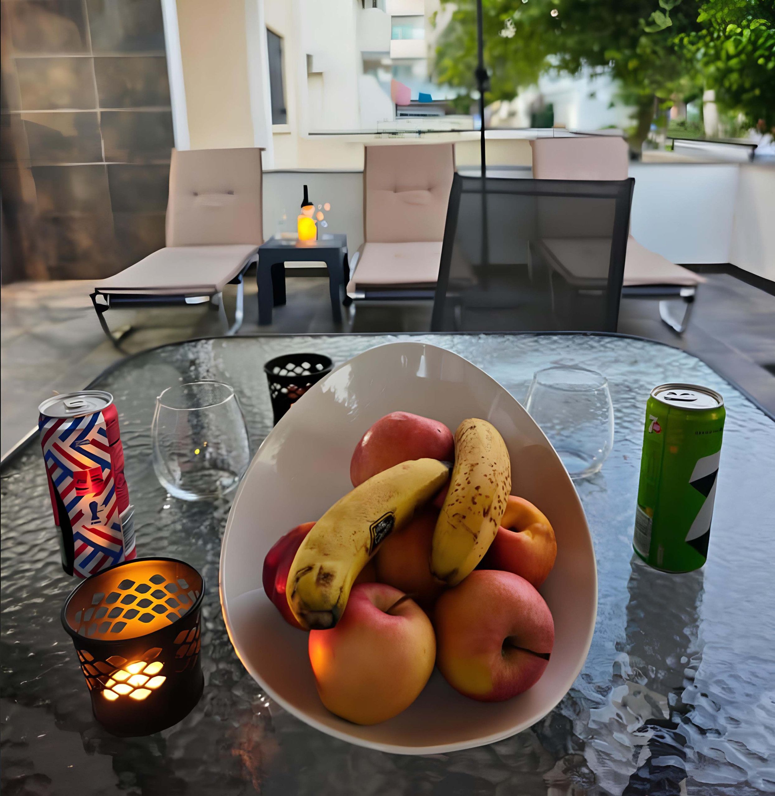 Ein Tisch mit Obstschale, einer Limodose, einem Glas und einer Kerze.