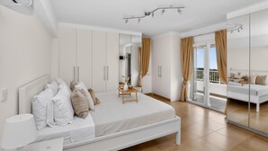 Un dormitorio moderno con cama, mesita de noche, lámpara, armario y un espejo grande.