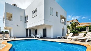 Un moderno edificio de dos pisos con piscina, sillas de descanso y un área de patio.