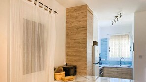 Une cuisine moderne avec des meubles en bois, un plan de travail en marbre et une fenêtre agrémentée d’un rideau à motifs.