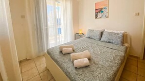 Une chambre à coucher avec un lit, des oreillers, une table de chevet, une lampe et un tableau au mur.