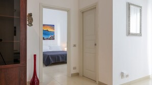 A hotel room with a bed, a painting, a red vase, and a wooden cabinet. - GuestHost - Large 160 sqm apartment, ideal for groups or families up to 6, located on the first floor of a building with an elevator (NOT for guests with disabilities).The property is located in a quiet area, yet fully served by all main amenities and we (Palermo)
